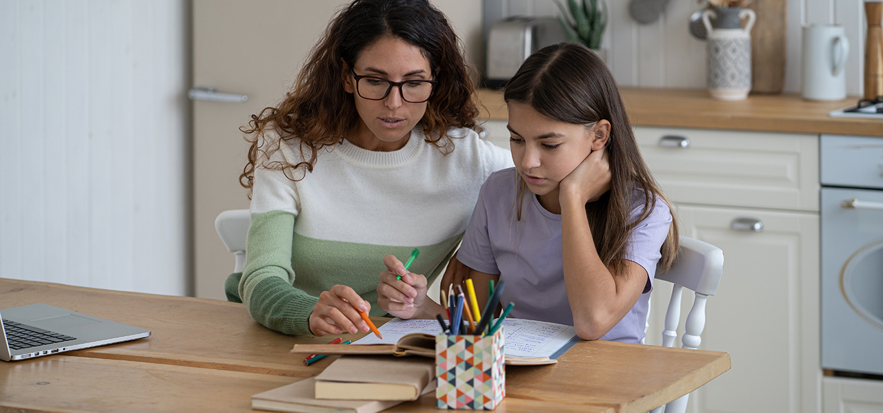 Homeschool parent helps teenage girl with schoolwork