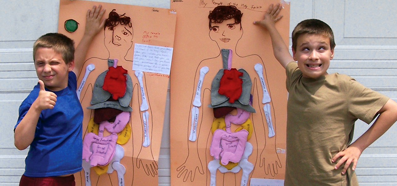 Two homeschooled boys pose in front of their human body models completed in Behold and See 4 science