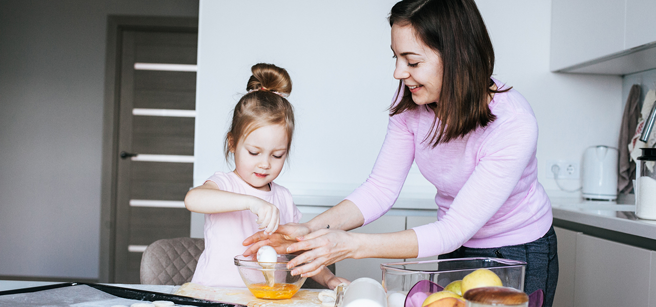 Preschooler helps mother with cooking in the kitchen