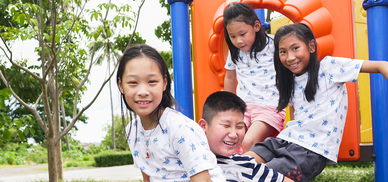 Happy Asian kids sitting at playground together in the park