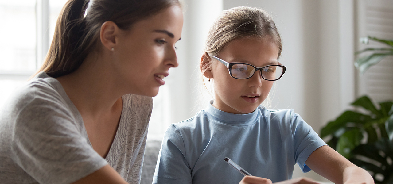 Young mother helps daughter with schoolwork