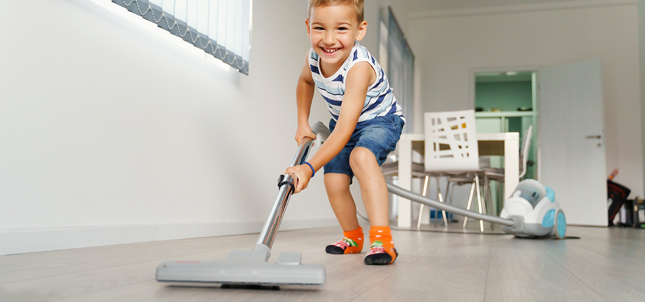 Young boy cheerfully vacuums floors