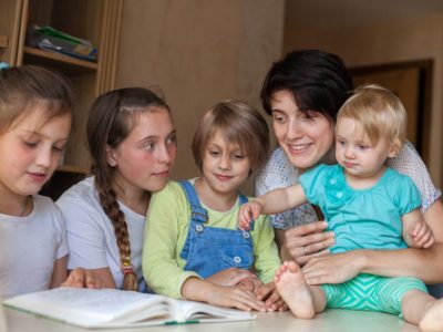 Enthusiastic,Children,Read,Book,At,Table,With,Their,Mother