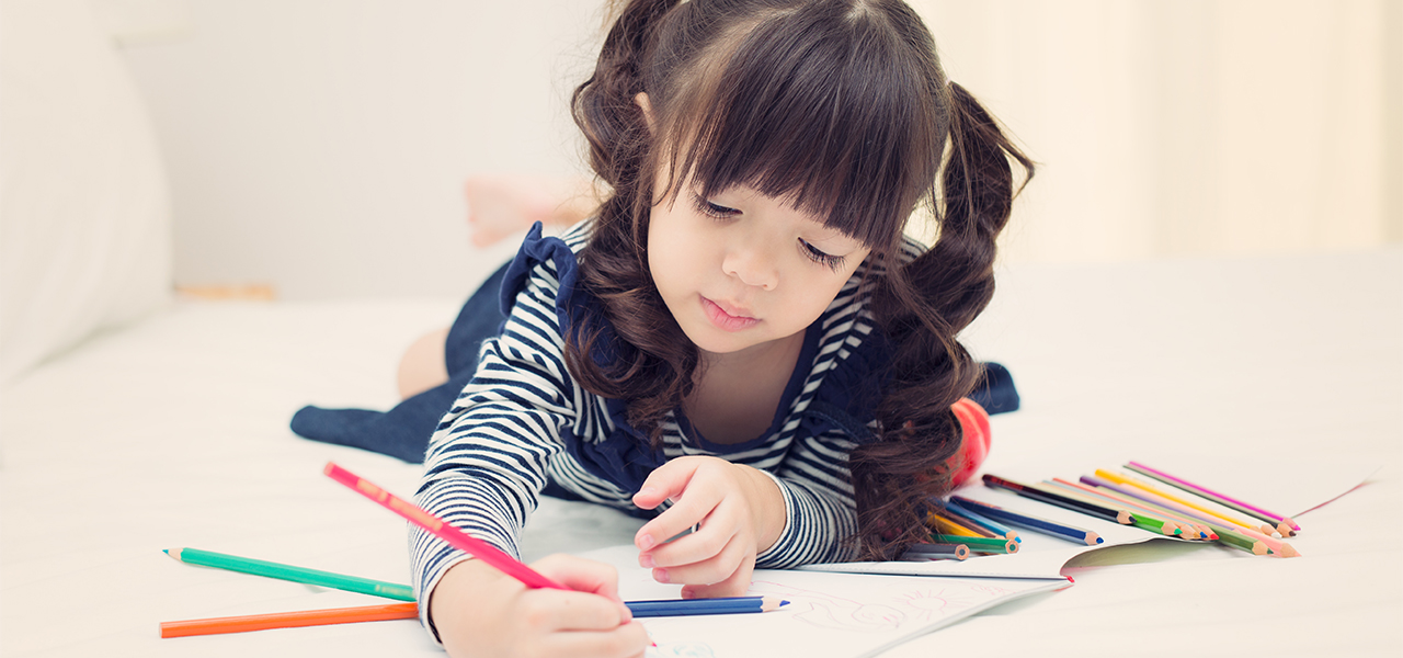 Little girl writes with colored pencils